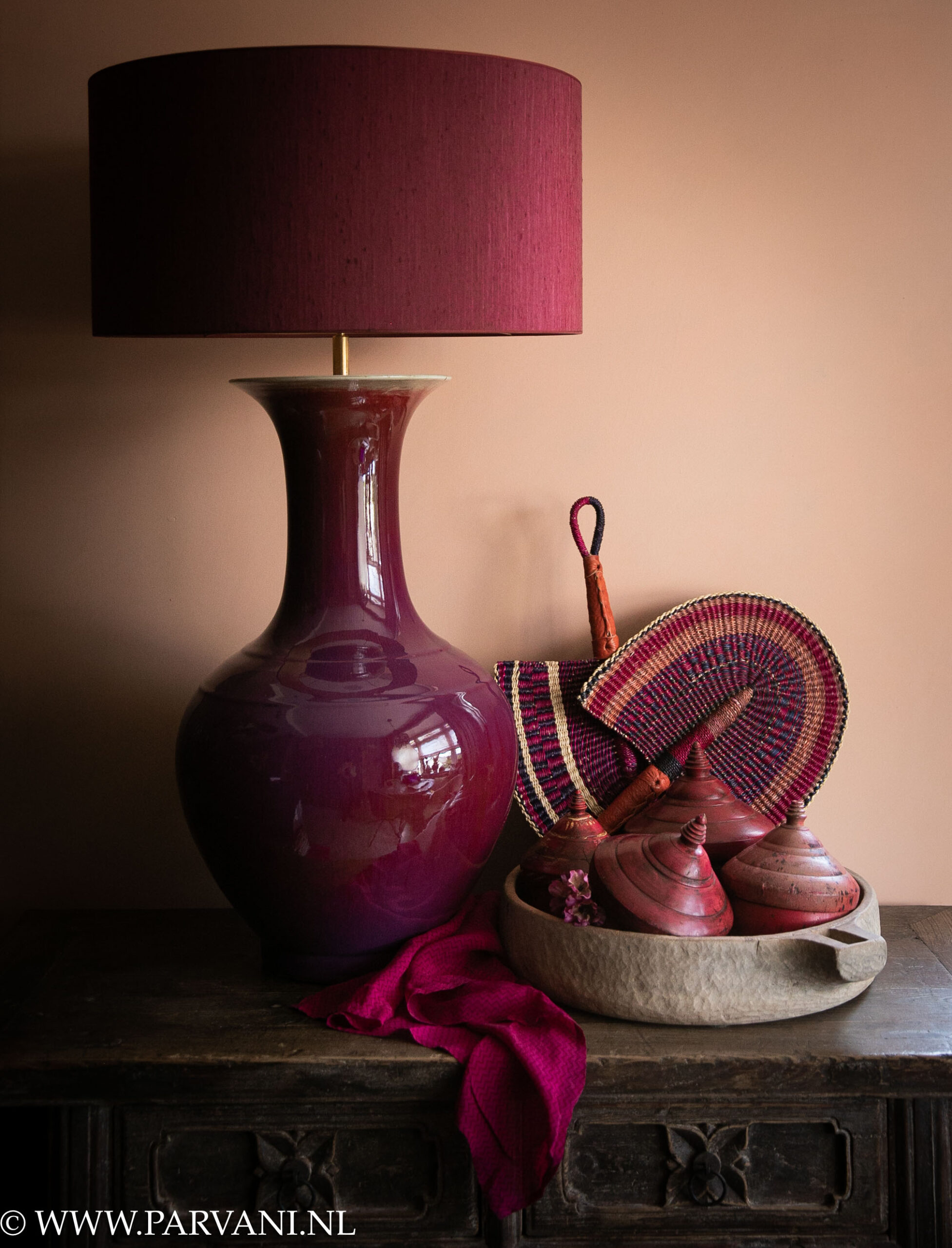 Grote paars roze tafellamp uit China met Burgundy kleurige lampenkap, stenen schaal met oude Indiase tika potjes en kleurrijke Afrikaanse waaiers