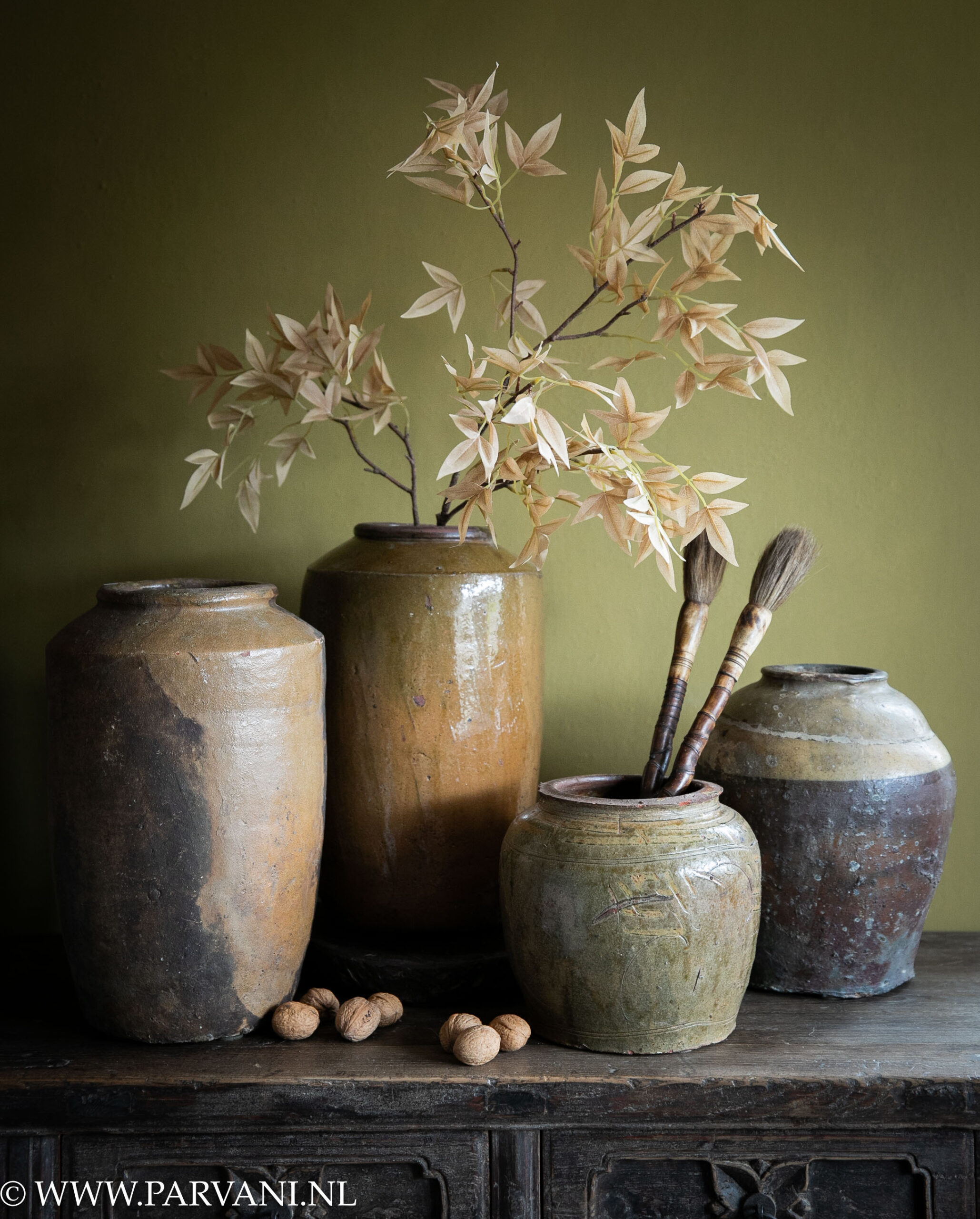 Oude aardewerk potten kruiken uit China in olijfgroen mosterd oker bruin met bamboe kwasten en tak met roze bla