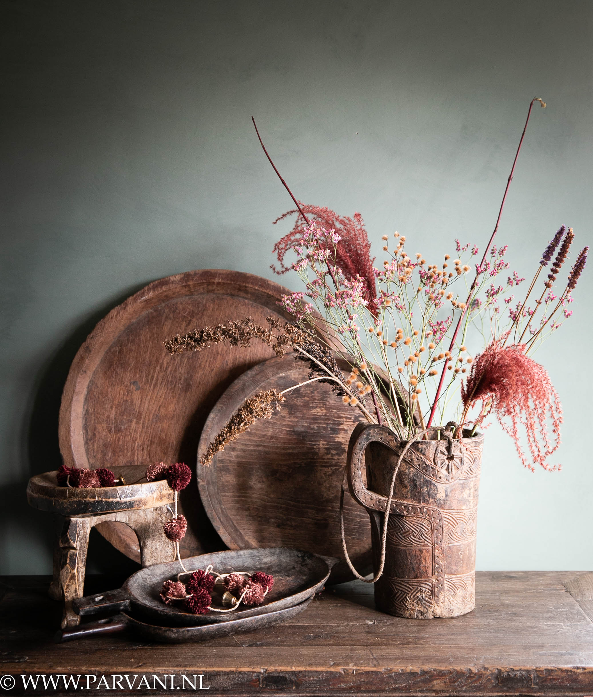 Oude houten naga schalen uit India met unieke kan met snijwerk, droogbloemen, pompom slinger en Afrikaans krukje
