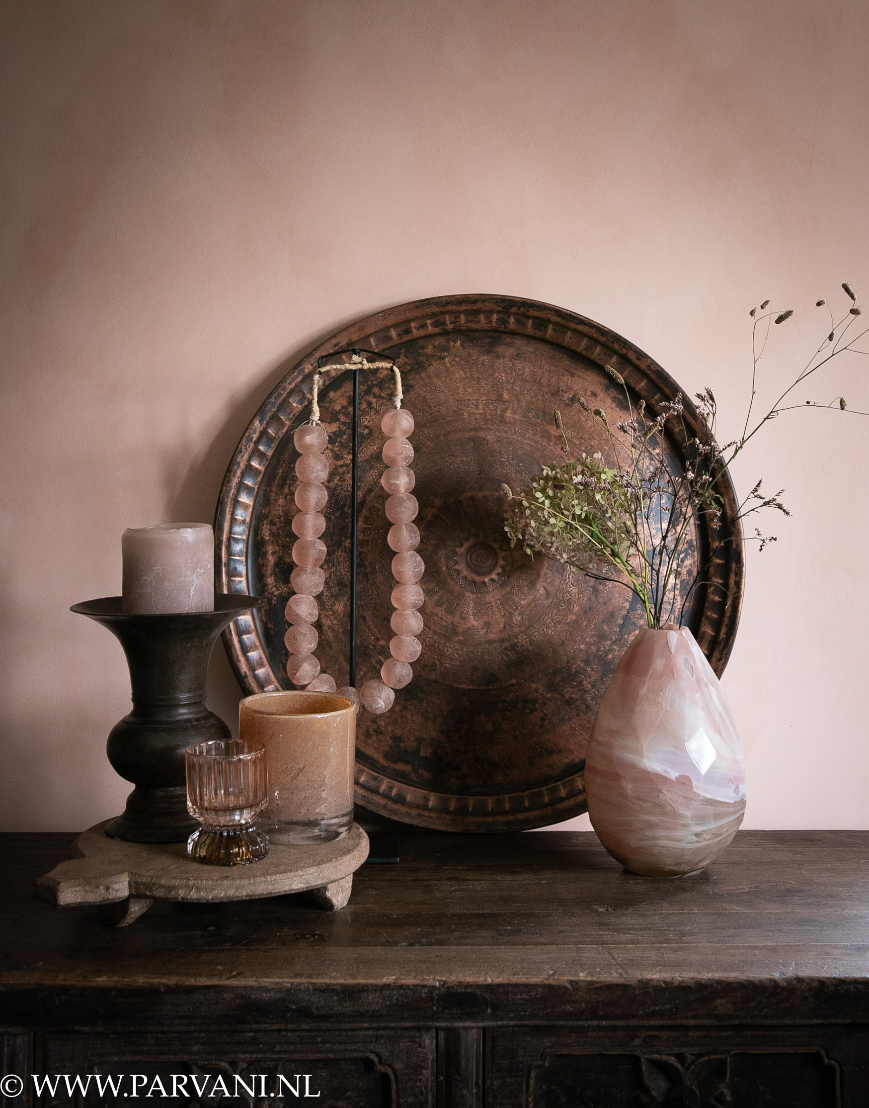 Oud roze accessoires met koperen dienblad, glazen vaas, ketting op standaard en kandelaar met windlichten