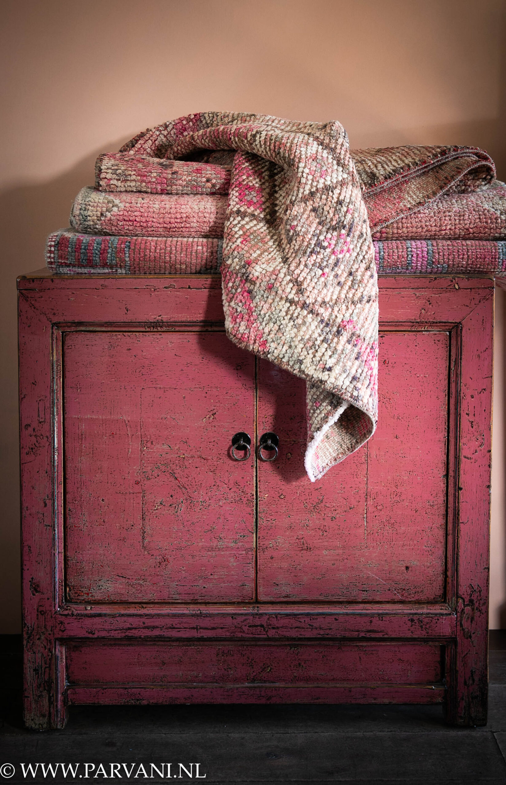 Roze 2 deurs lakwerk kastje uit China, met vintage wollen kelim lopers in warme roze kleuren