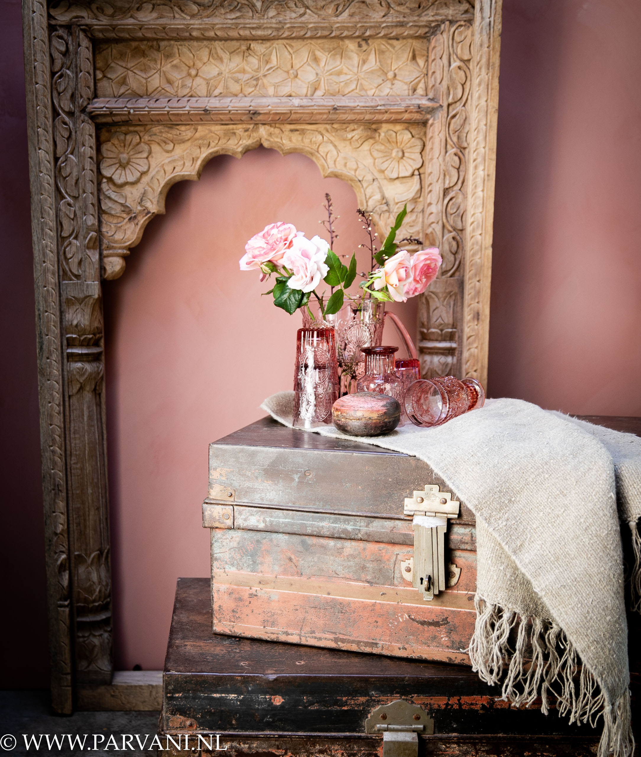 Spiegel houtsnijwerk met oude metalen koffers uit India met erop kleurrijk glaswerk