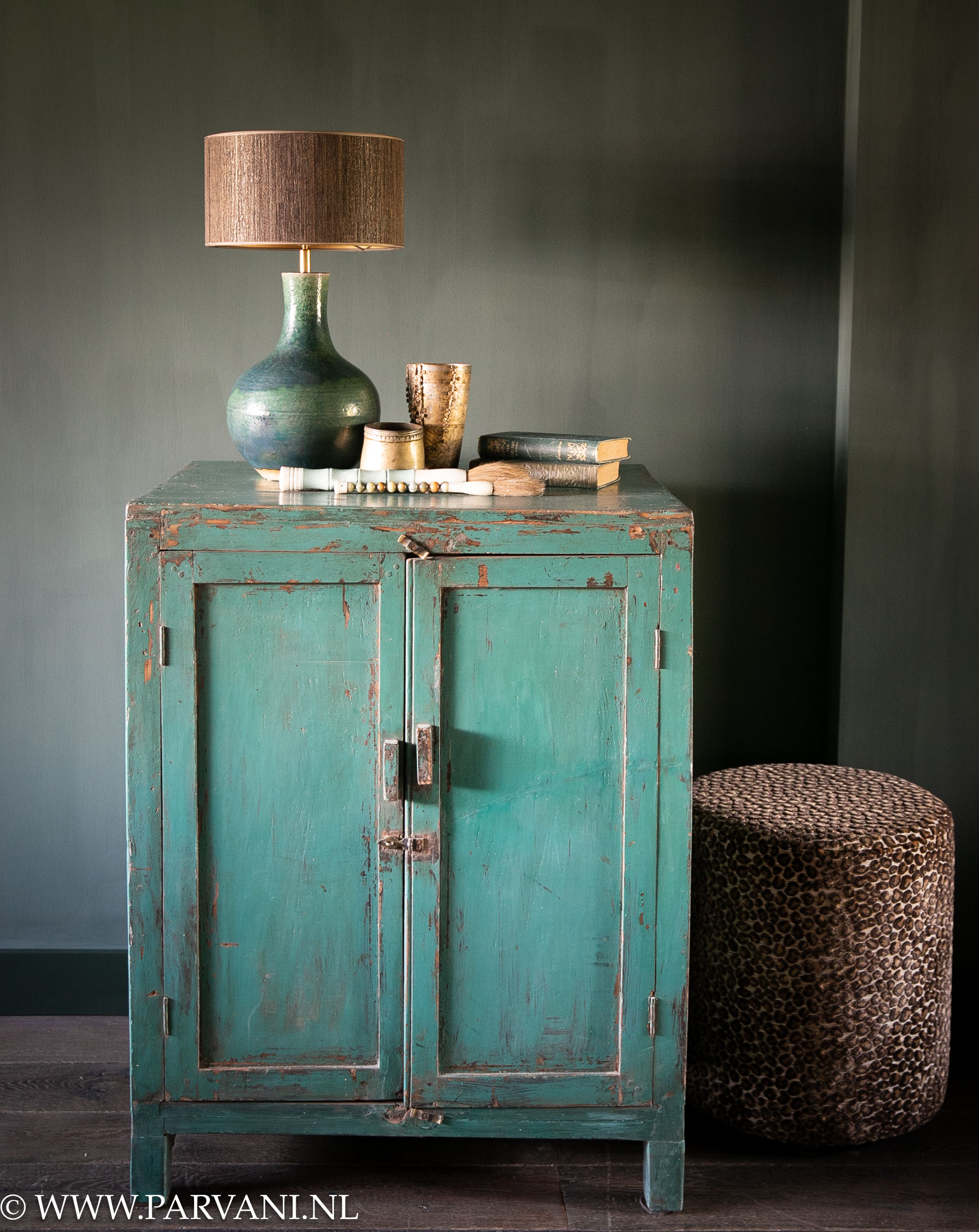 Oude groene kast met deuren uit India met Chinese tafellamp, accessoires en bruine ronde luipaard poef