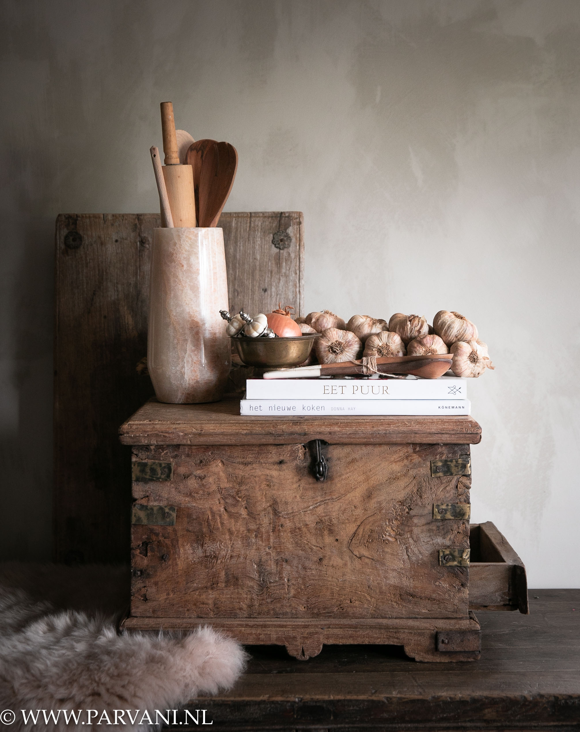 Unieke oude houten kist uit India met metaalbeslag en lade gedecoreerd met keuken accessoires, bajot tafeltje en schapenvacht