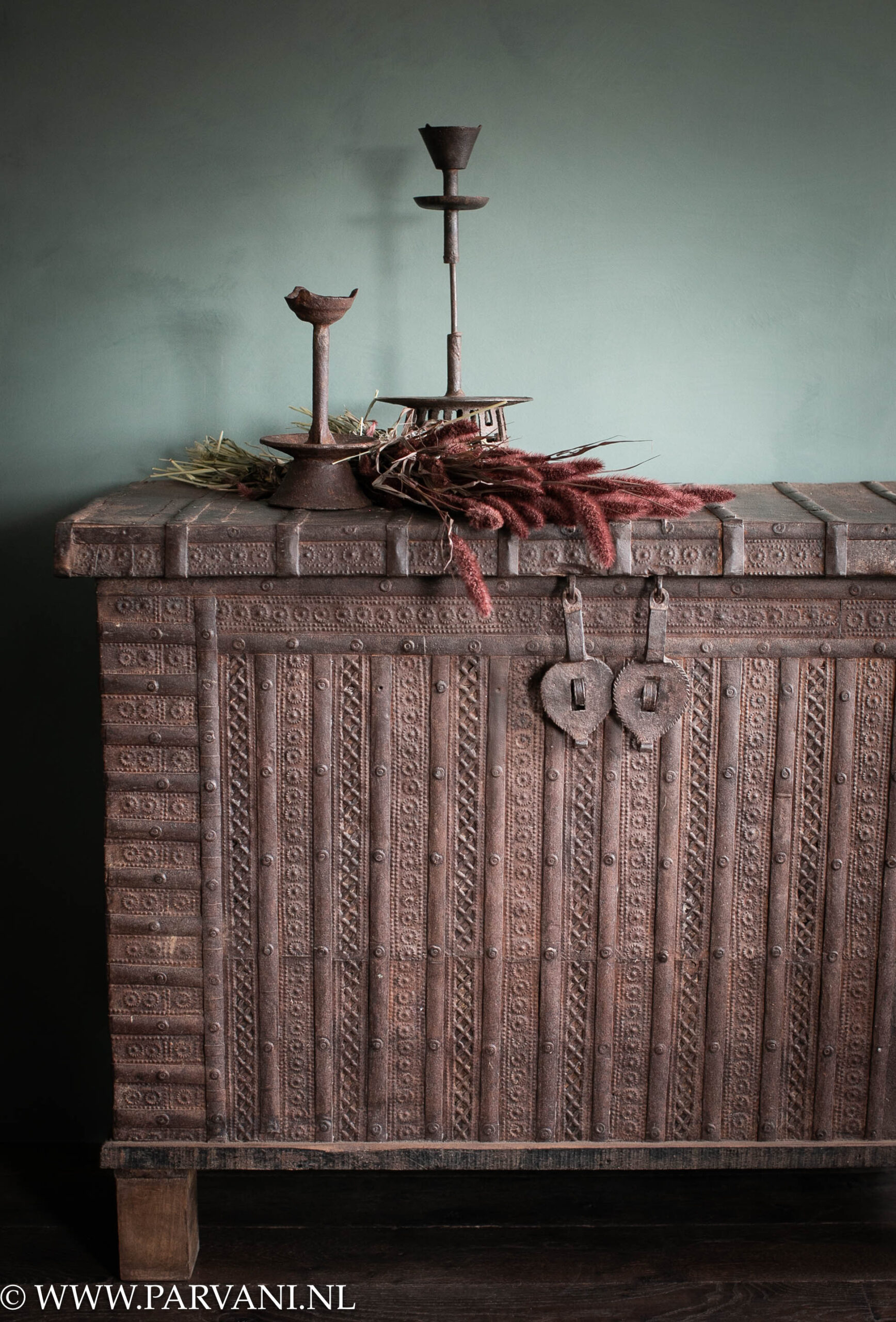 Grote hoge smalle houten kist met decoratief ijzerbeslag uit India met bruine metalen kandelaren