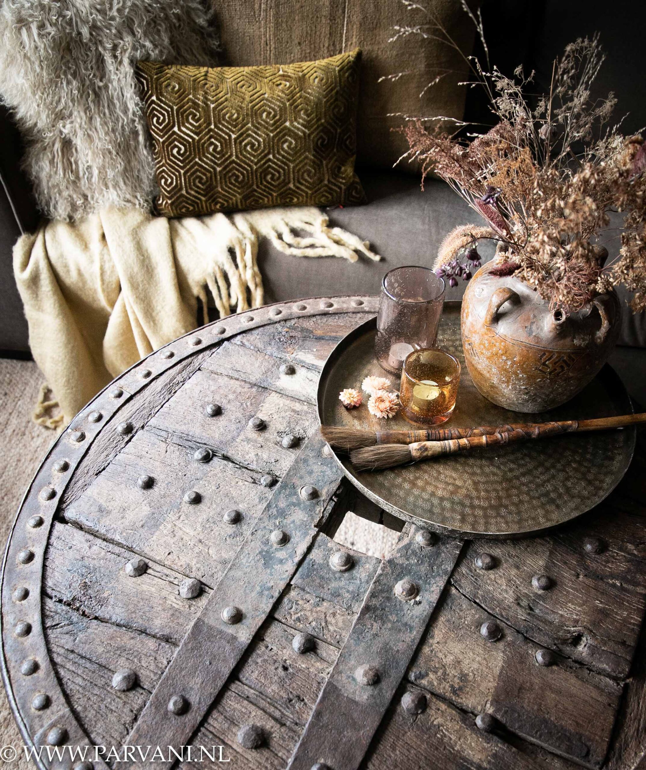 Grote ronde salontafel gemaakt van een stoer oud houten wiel met metalen rand, siernagels en smeed ijzeren poot