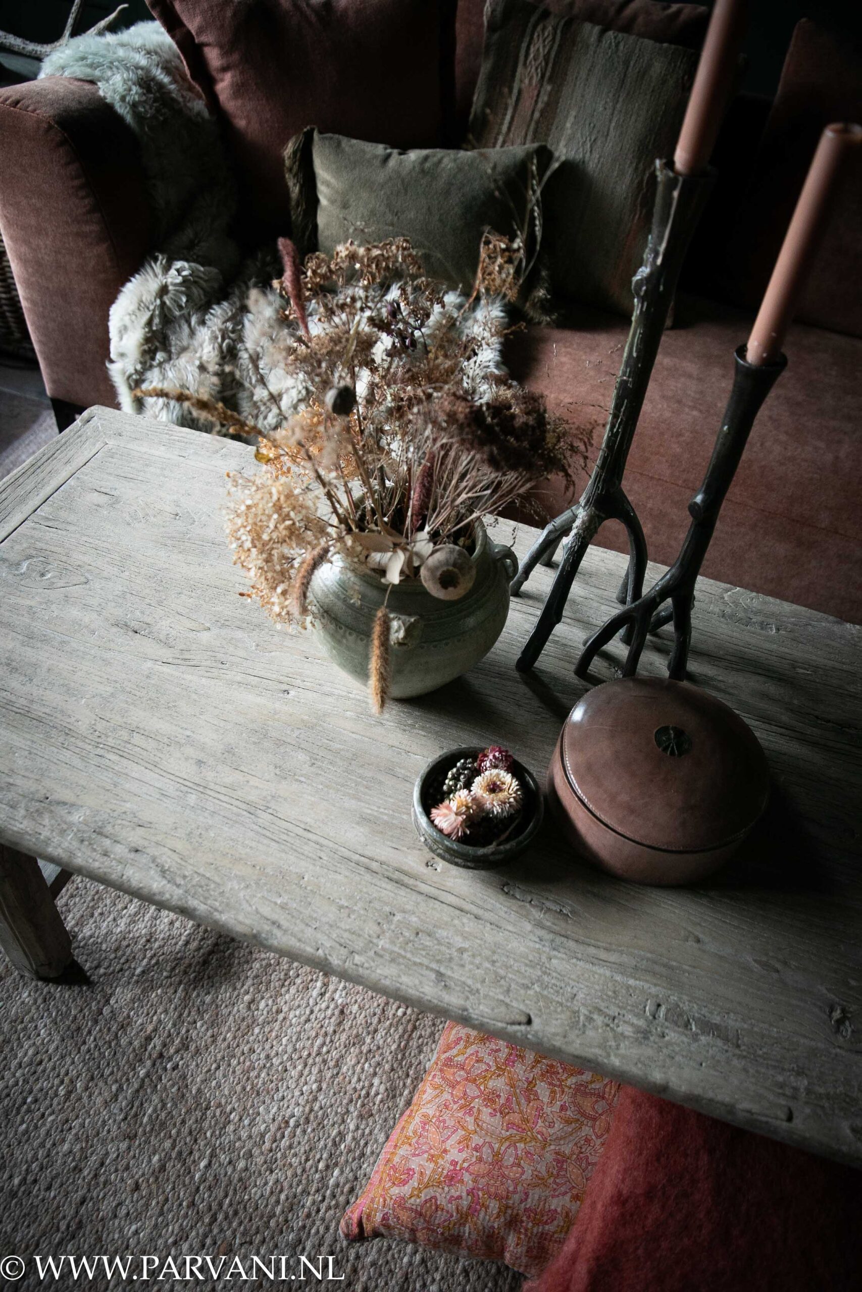 Lange smalle oude salontafel uit China van licht naturel kleurig hout met houten poot, terra roze bank, vloerkussen en plaid met sierkussens