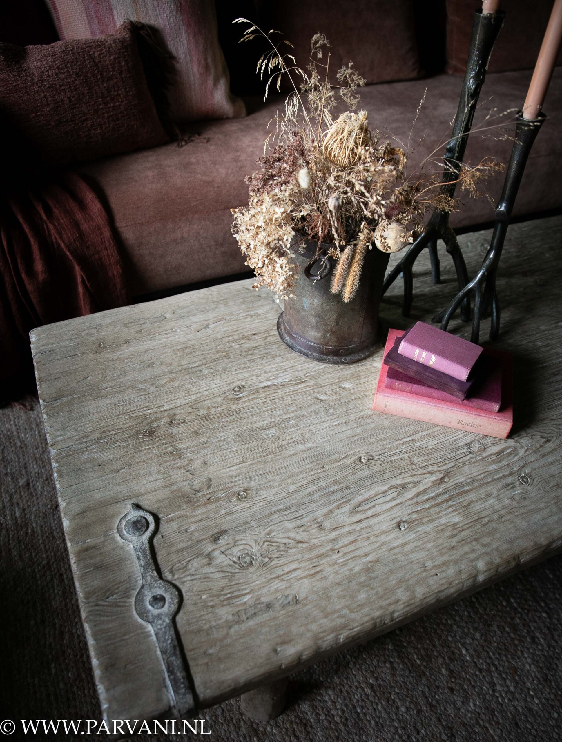Langwerpige houten salontafel gemaakt van oude deur met metaalbeslag in lichte kleur en met mooi geleefd blad