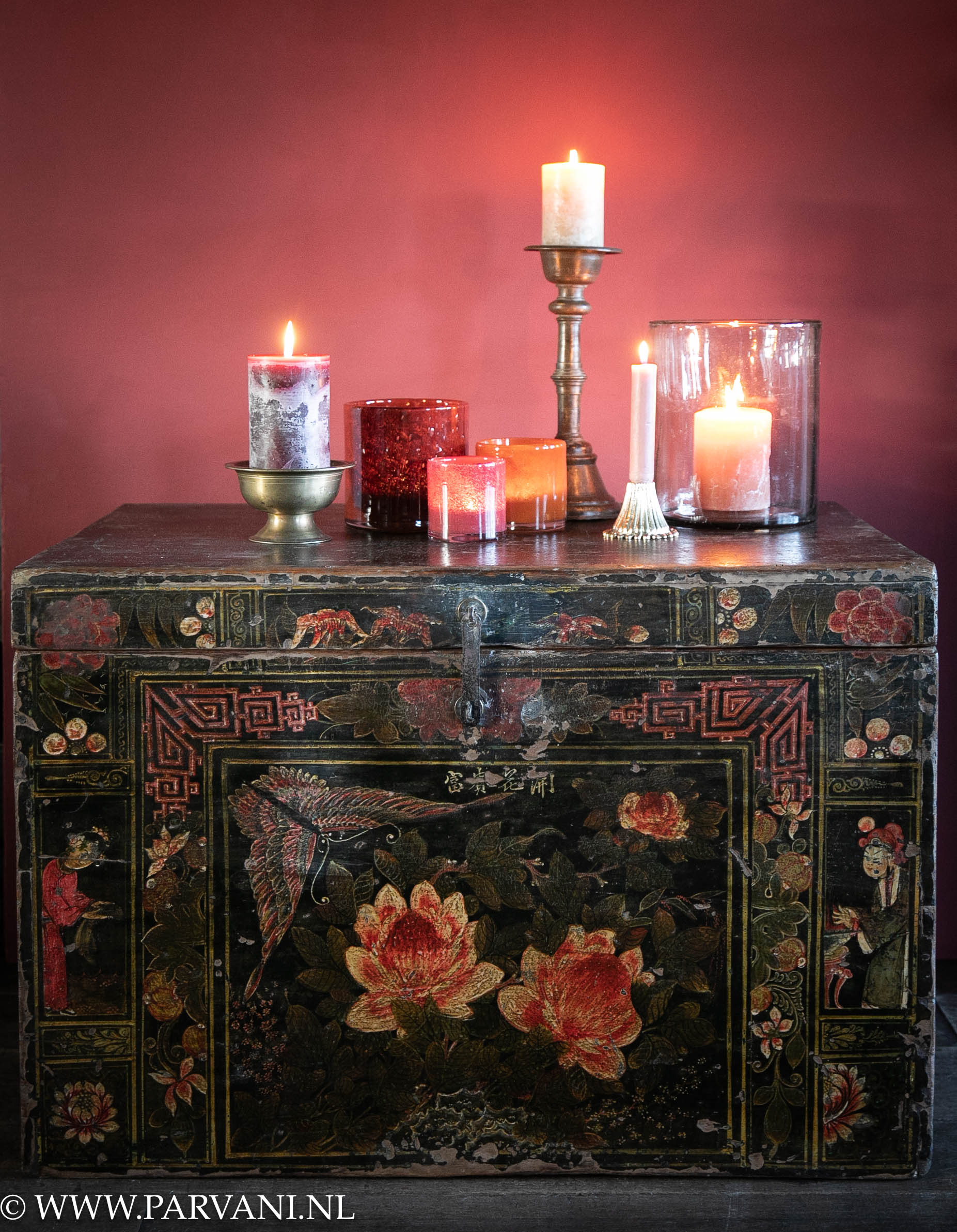 Oude Chinese houten kist in zwarte kleur met beschildering in warme tinten rood en oranje met kaarsen, kandelaars en glazen windlicht en waxine houders
