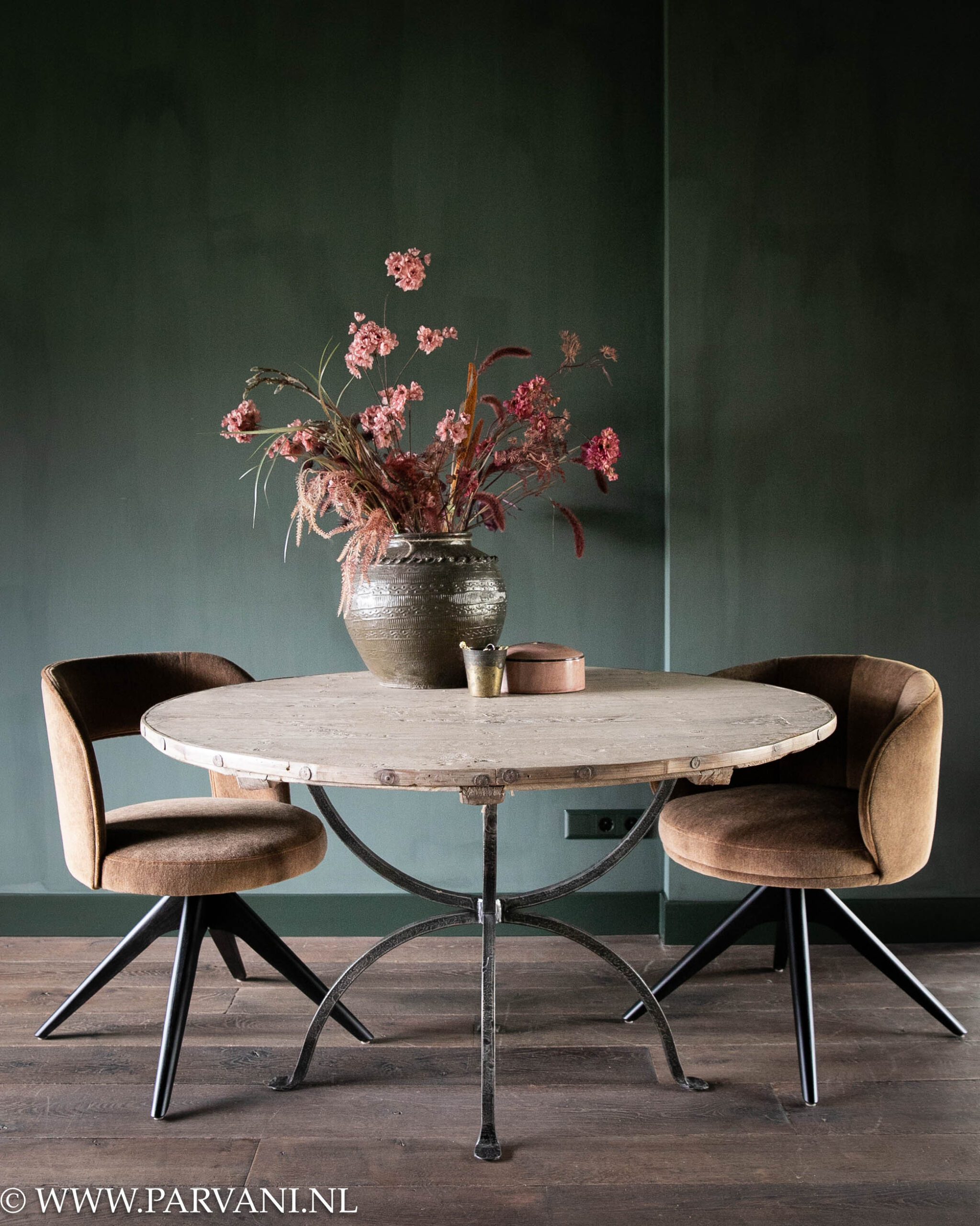 Ronde eettafel met oud houten blad en smeedijzeren onderstel, met rond model eetkamerstoelen op draaipoot