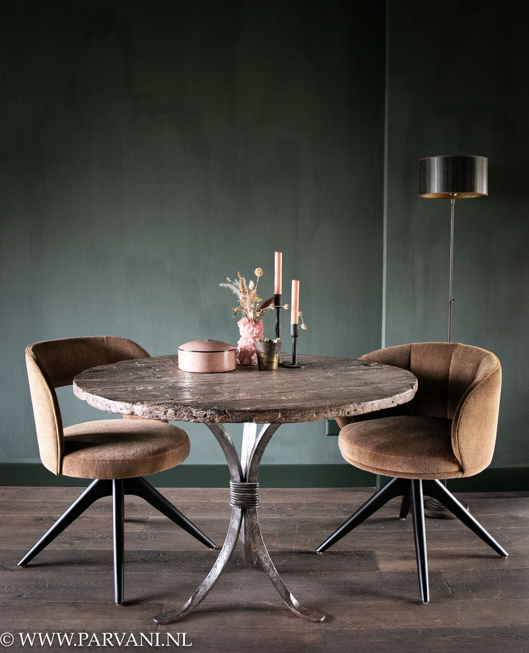 Ronde eettafel met robuust oud houten blad en smeedijzeren onderstel met eetkamerstoelen in brons kleurige mohair velvet stof en draaipoot