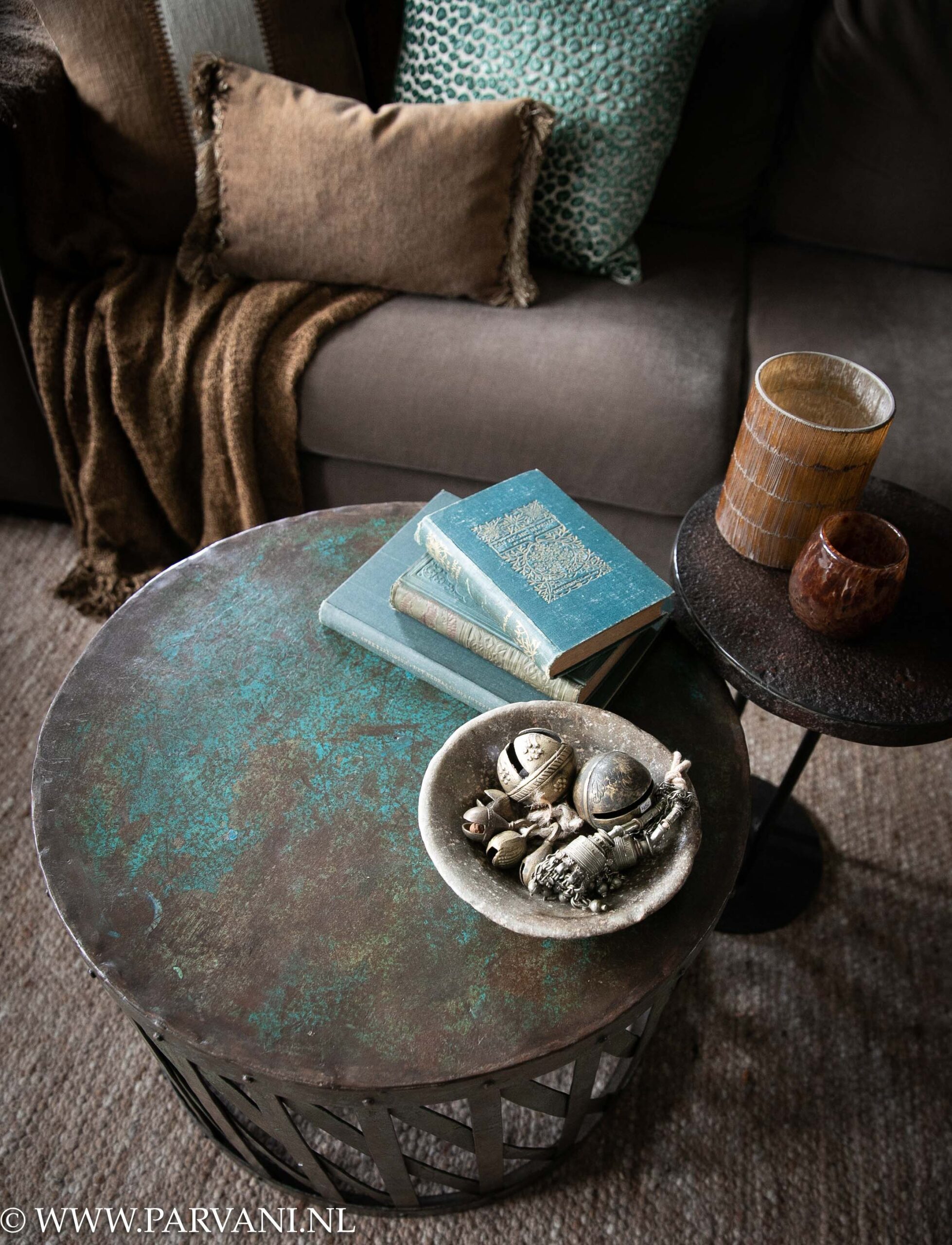 Ronde metalen bijzettafel salontafel uit India met blauw groene kleur patina en klein rond ijzeren bijzet tafeltje en bruin turquoise accessoires en kussens