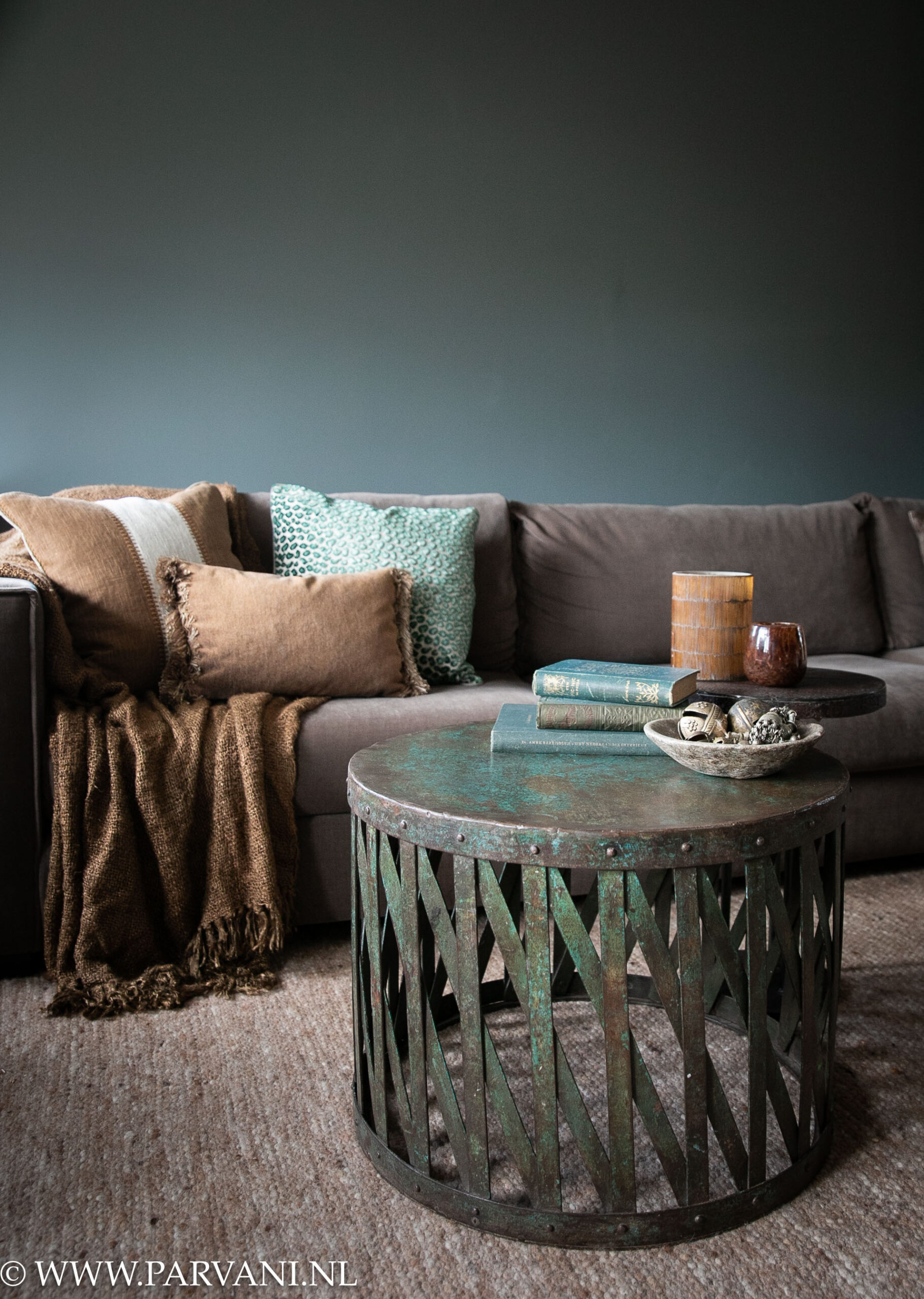 Ronde metalen salontafel bijzettafel uit India met blauw groene kleur patina en klein rond ijzeren bijzet tafeltje en bruin turquoise accessoires en kussens