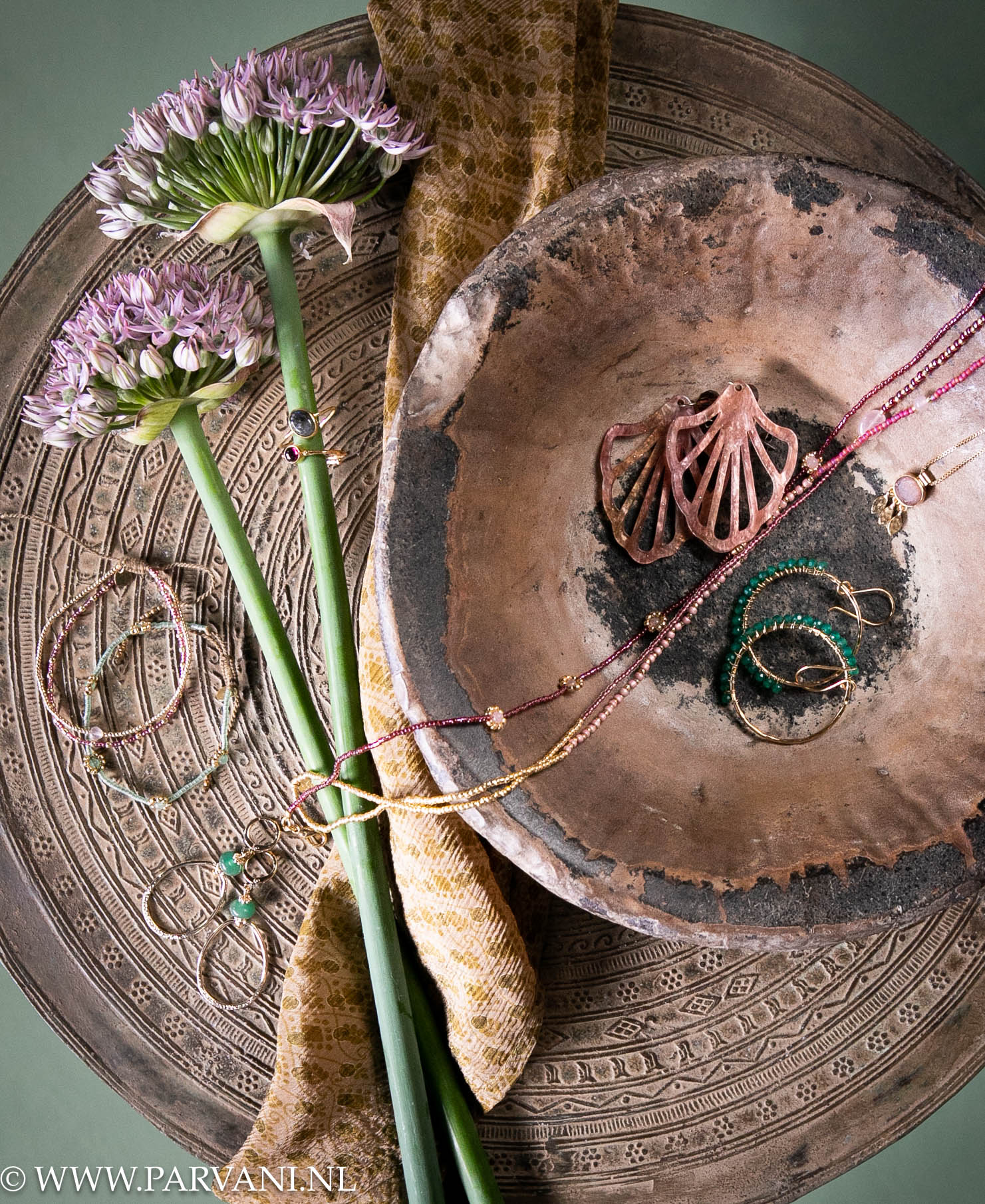 Bronzen drumtafel met oude schaal met fairtrade sieraden met edelsteen in roze, paars en groene kleuren