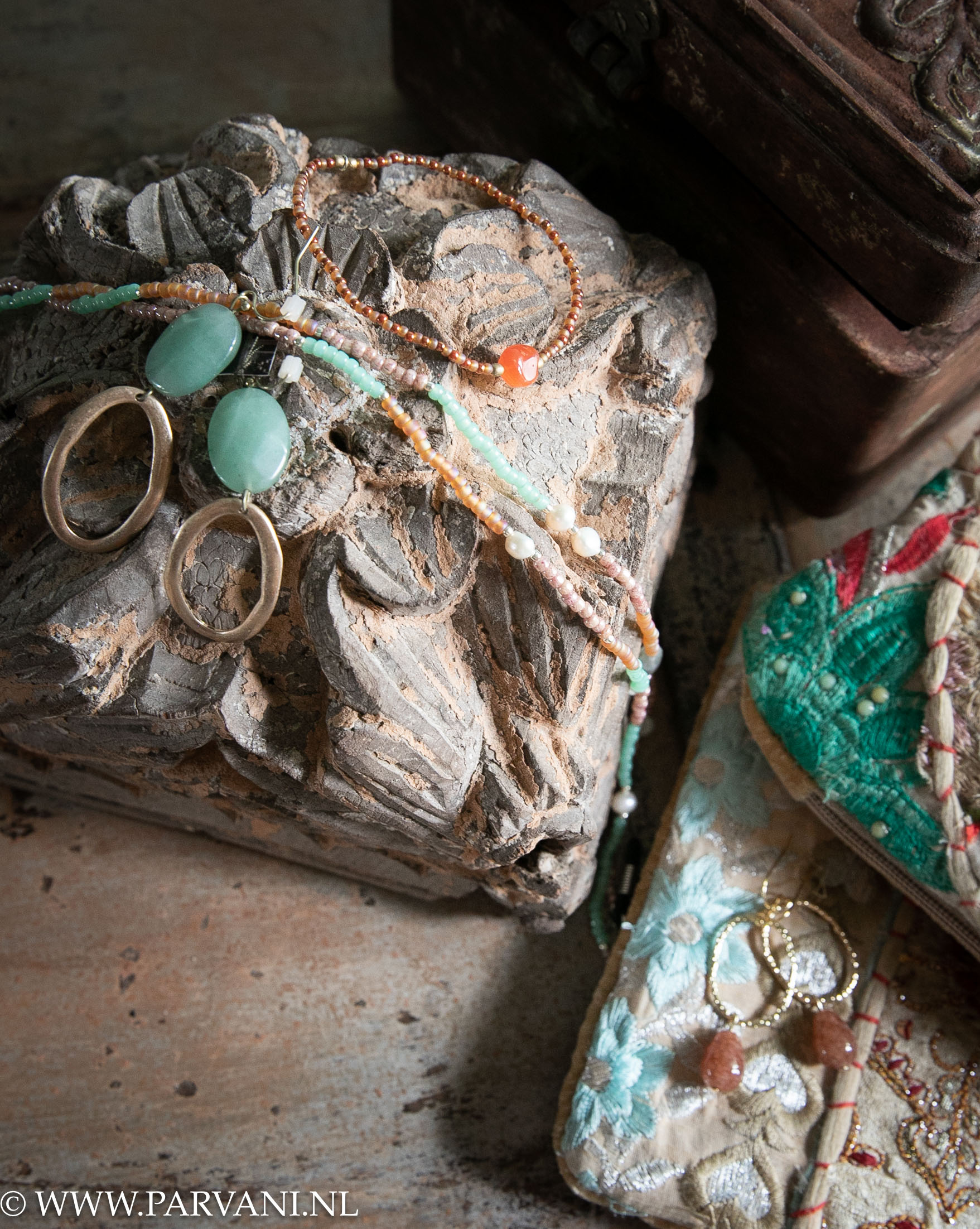 Houten ornamenten uit India met fairtrade sieraden met edelsteen in warm oranje en groene kleuren en kleurrijk toilettasje